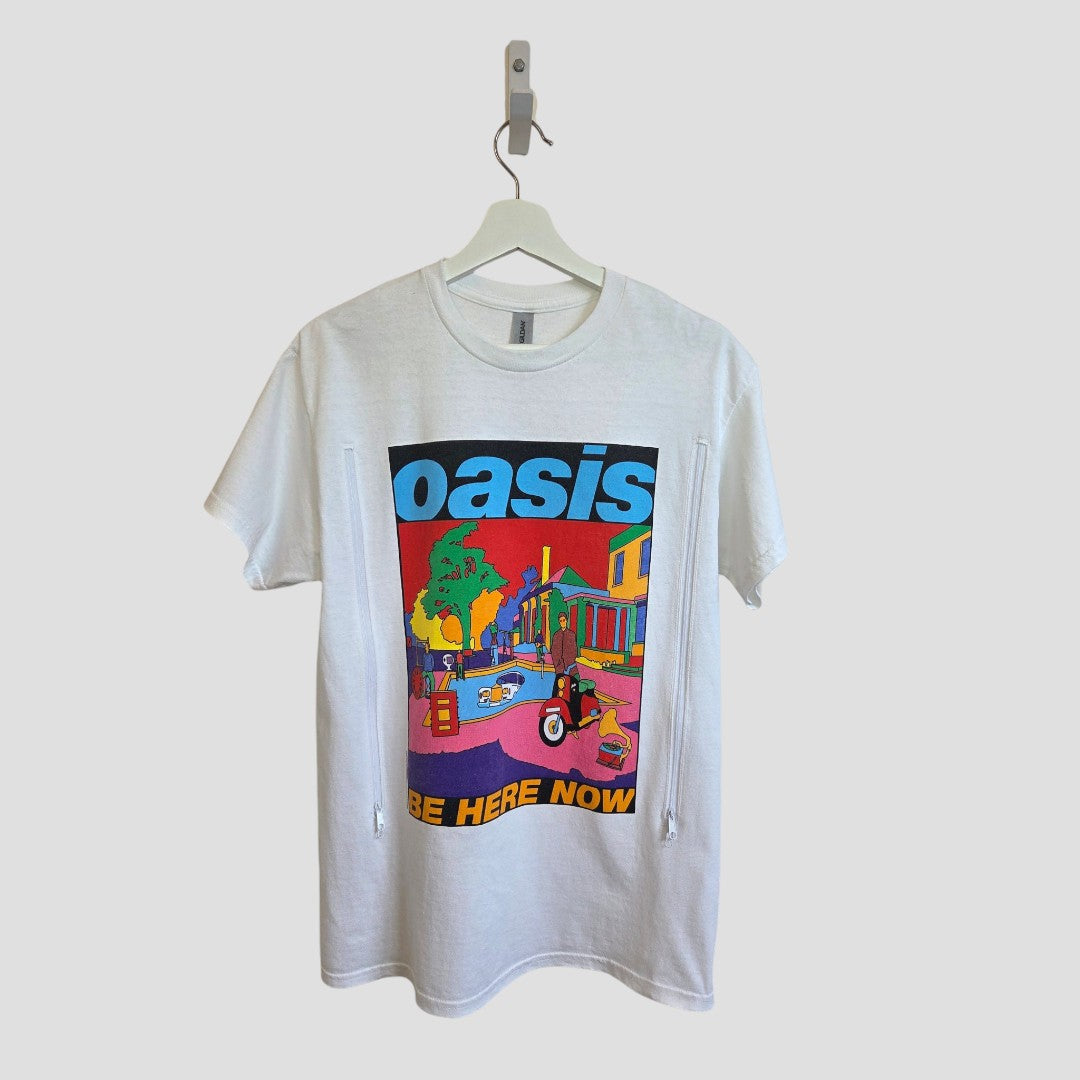 The Gildan Upcycled Breastfeeding & Pumping Oasis Band T-shirt in white (M, 100580) features a vibrant cartoon street scene and bold "oasis" and "Be Here Now" text, blending comfort and style for nursing moms.