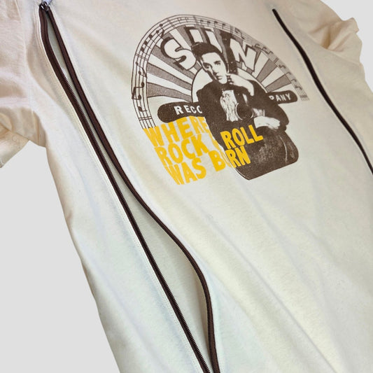 The Amplified Upcycled Breastfeeding & Pumping Cream Elvis Presley Band t-shirt (L) is an eco-friendly white shirt with two vertical zippers and a graphic of a man holding a guitar, featuring "SUN RECORD COMPANY" and "WHERE ROCK & ROLL WAS BORN" in yellow and black.