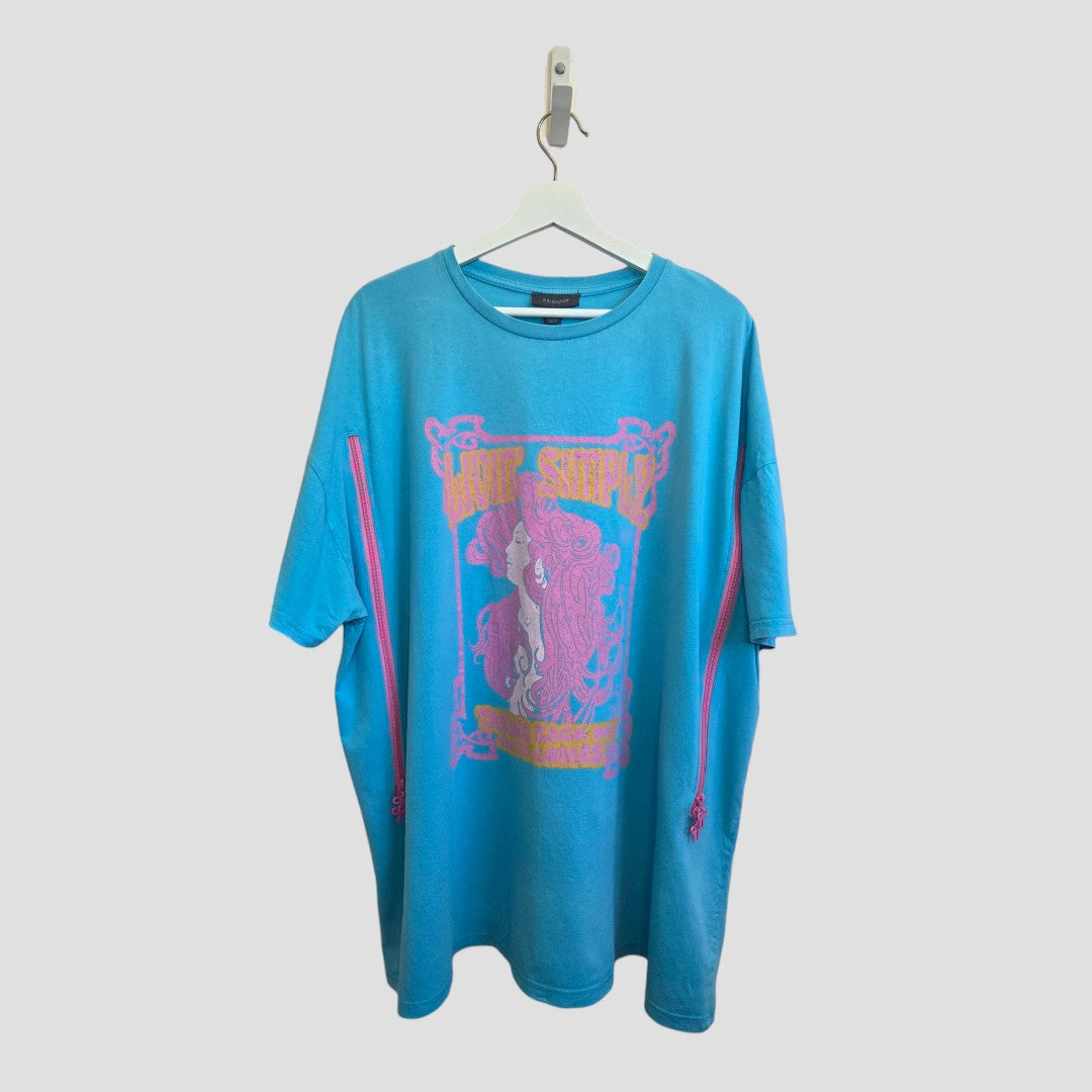A Primark Upcycled Breastfeeding (Nursing) & Pumping Turquoise/Pink Girl t-shirt in size XL (UK18/20) (100516), featuring a vibrant turquoise color with a graphic of a woman in pink and yellow along with bold text, is displayed on a white hanger against a light gray background.
