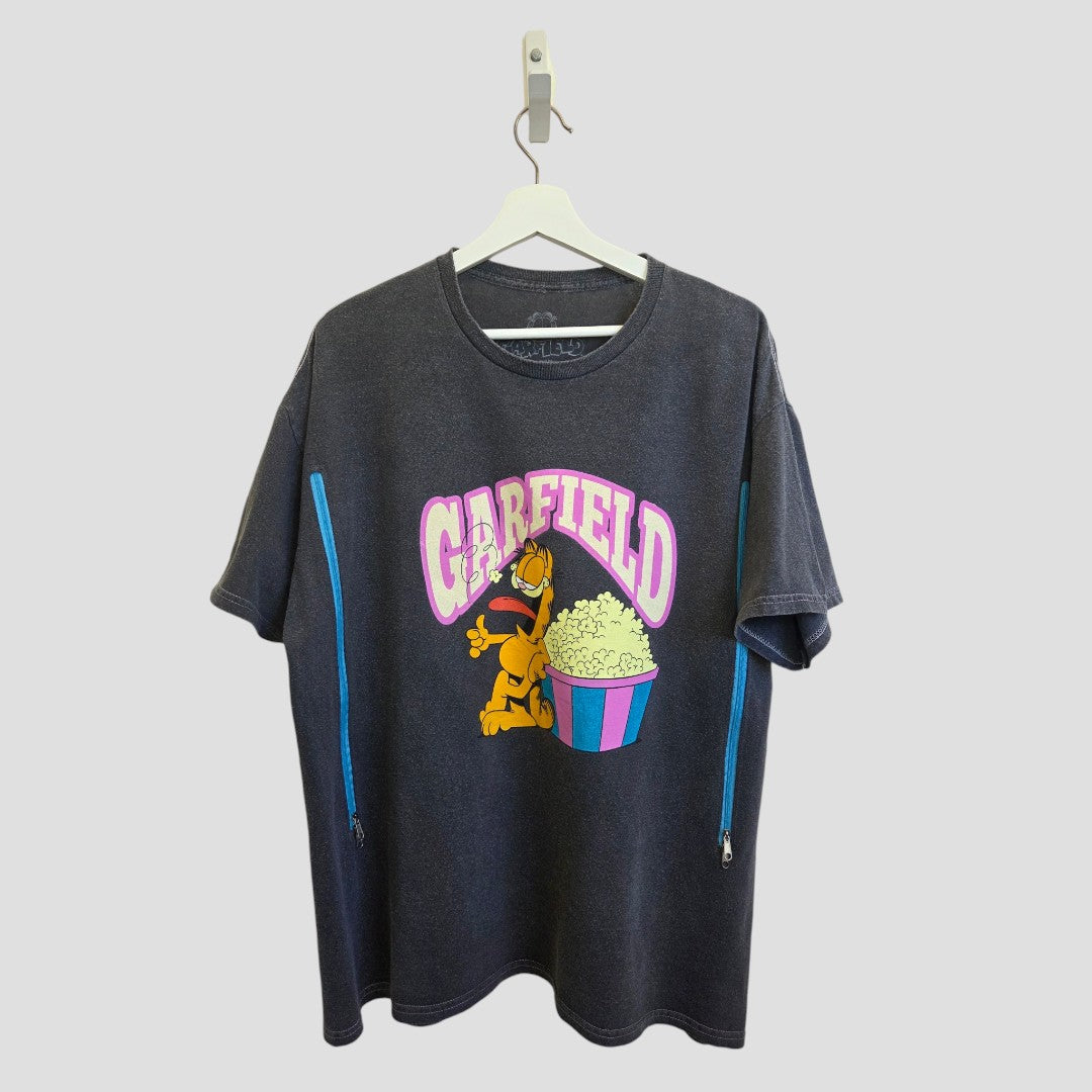 The Garfield Upcycled Breastfeeding (Nursing) & Pumping Garfield Popcorn t-shirt L (100518) by Garfield is a black T-shirt on a hanger featuring Garfield eating popcorn, with "Garfield" in large pink letters above. Blue zippers on each side make this shirt both stylish and practical for nursing or pumping.