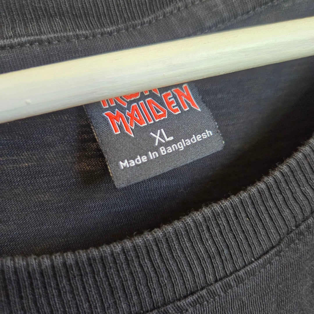 A close-up of a black Primark shirt on a hanger shows a label reading "IRON MAIDEN XL Made In Bangladesh" in white and red text, highlighting this Upcycled Breastfeeding (Nursing) & Pumping Black Iron Maiden Lace Band t-shirt XL (100567) as an eco-friendly and practical choice for those seeking stylish breastfeeding clothing.