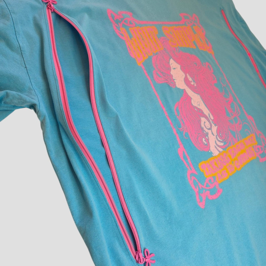 Introducing the Primark Upcycled Breastfeeding (Nursing) & Pumping Turquoise/Pink Girl t-shirt in XL (UK18/20) (100516). This affordable and stylish turquoise shirt features pink zippers running from the armpit down each side for easy nursing access, along with a vibrant pink and yellow graphic of a woman with flowing hair on the front. Ideal for those seeking comfortable breastfeeding clothing that doesn't compromise on style or functionality.