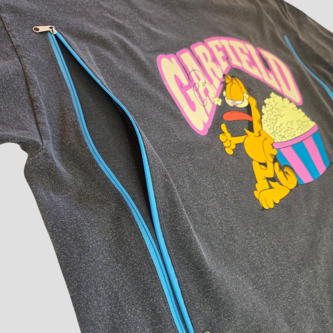 The Garfield Upcycled Breastfeeding (Nursing) & Pumping Popcorn t-shirt (size L) by Garfield features a cartoon of Garfield eating popcorn with pink "Garfield" text above, and two blue zippers running diagonally across the front for a fun and practical breastfeeding option.