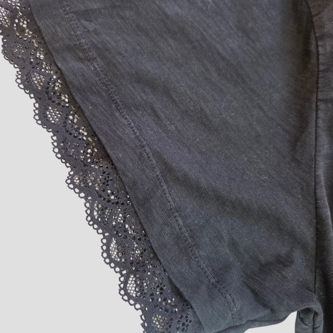 Close-up of the Primark Upcycled Breastfeeding (Nursing) & Pumping Black Iron Maiden Lace Band t-shirt XL (100567) showcasing black fabric with a scalloped lace trim along the edge. The delicate, floral-patterned lace adds a decorative touch to this eco affordable nursing clothing essential.