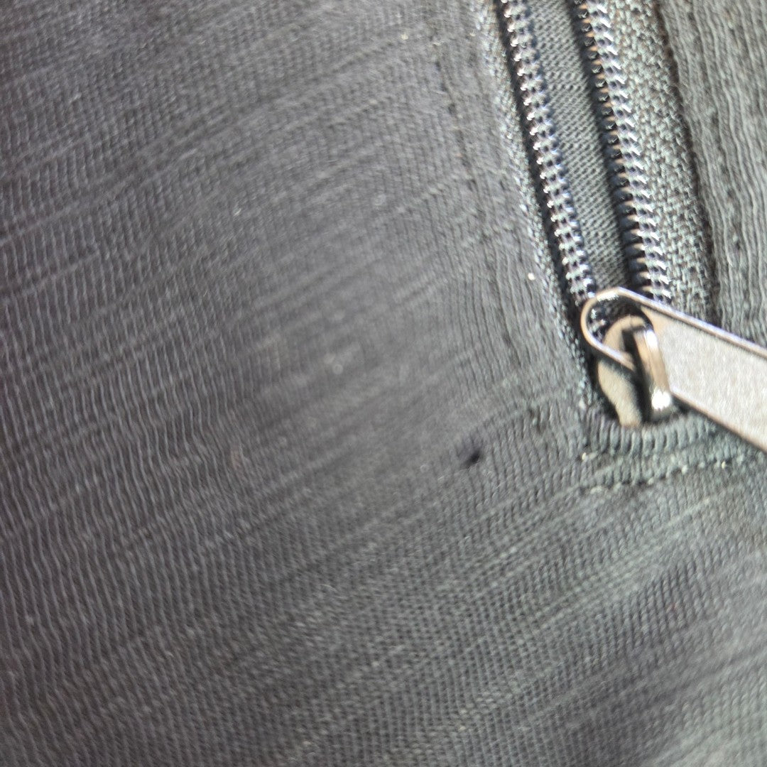 Close-up of a metallic zipper partially open on a piece of textured dark gray fabric, revealing detailed stitching around the zipper area—designed for eco-friendly and affordable nursing wear. The Primark Upcycled Breastfeeding (Nursing) & Pumping Black Iron Maiden Lace Band t-shirt XL (100567) combines functionality for breastfeeding and pumping with a stylish, sustainable design.