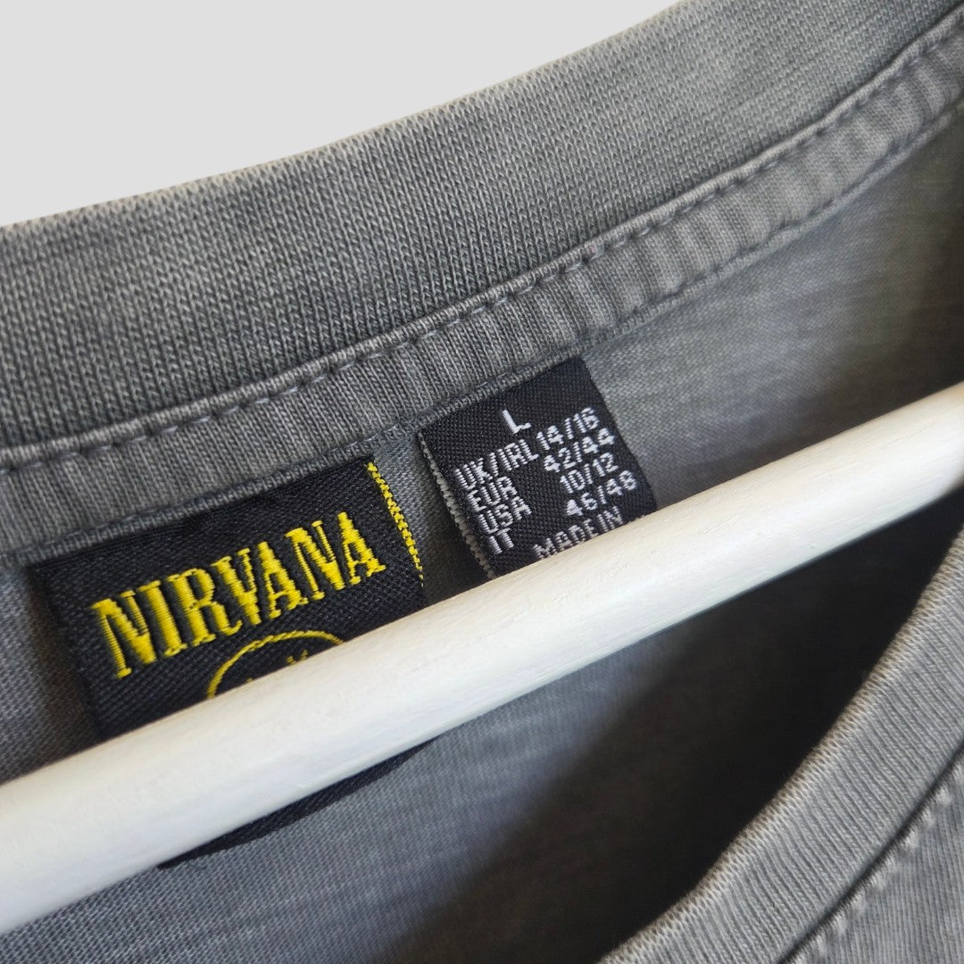 Close-up of the collar of a grey and pink upcycled Nirvana band t-shirt dress by Primark, made for breastfeeding and pumping from eco-friendly fabric. The neckline features a black and yellow Nirvana logo tag and size labels showing L (UK14/16), displayed draped over a white hanger.