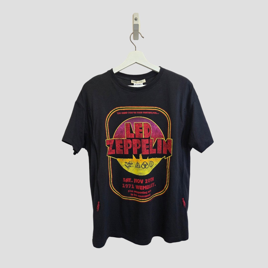 An upcycled Pull&Bear Led Zeppelin Wembley band t-shirt for breastfeeding and pumping (size M, 100575) features a colorful vintage-style graphic and tour details. Displayed on a white hanger against a plain gray background, this eco-affordable option offers stylish nursing clothing.