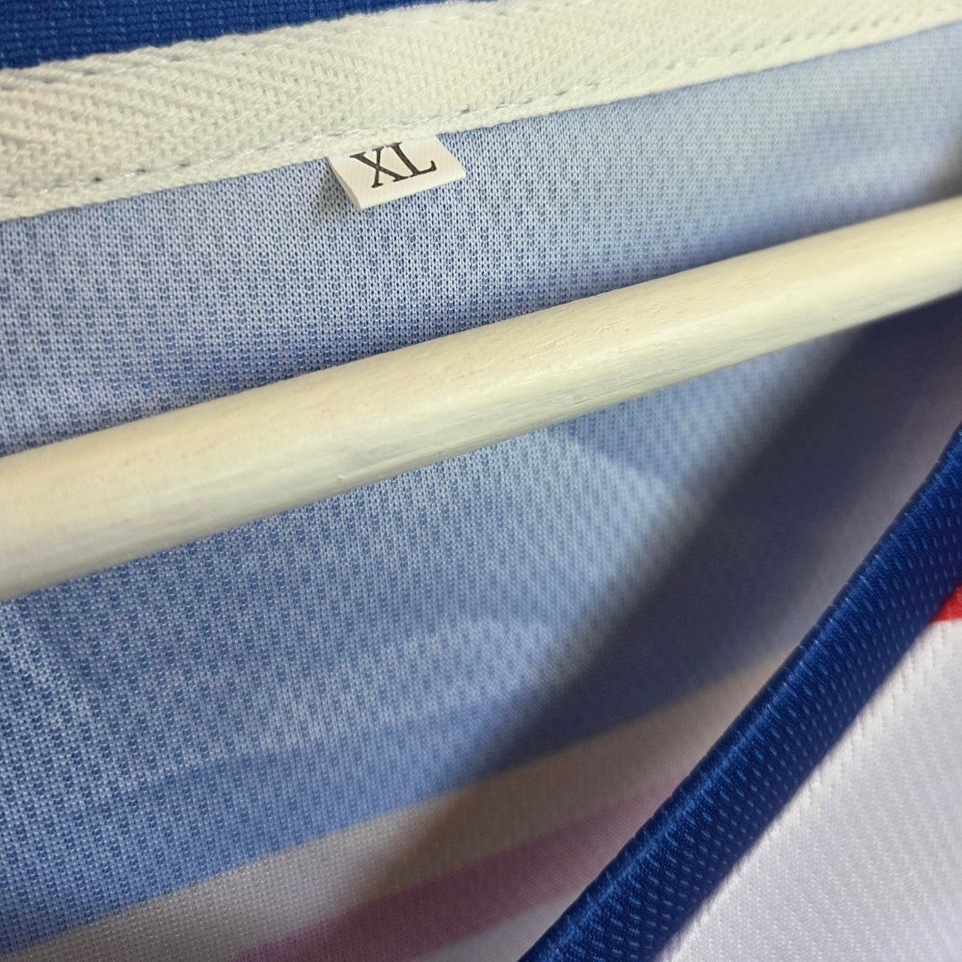 A close-up of a clothing label marked XL on the Amazon Upcycled Breastfeeding (Nursing) & Pumping White Off Campus Ice Hockey Jersey t-shirt (100599), displayed on a wooden hanger.