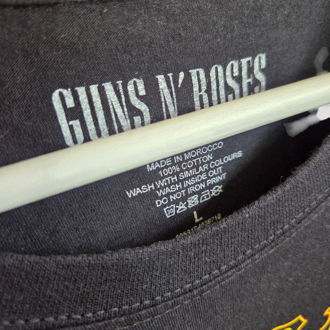 Upcycled Breastfeeding & Pumping Black Guns n Roses Surf Band t-shirt (size L) by Guns n Roses displayed on a hanger, highlighting the inside collar tags with Made in Morocco and care symbols—an eco-friendly choice for those seeking sustainable fashion.