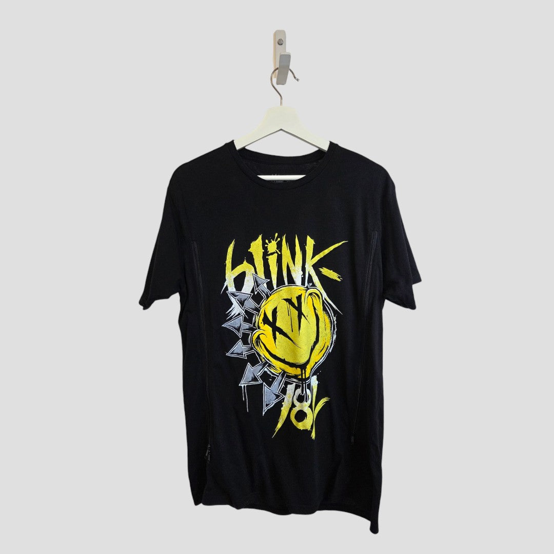 An upcycled Blink-182 Breastfeeding (Nursing) & Pumping black/yellow Smile Band T-shirt (size L), featuring a yellow smiley face graphic, graffiti-style “Link” text, and geometric shapes—offered as an eco-conscious choice for those seeking stylish and sustainable apparel. Displayed on a white hanger against a plain gray background.