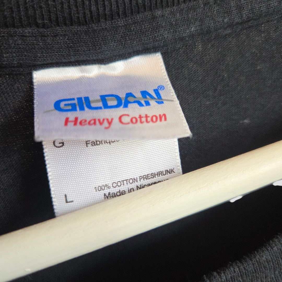 A close-up of a black t-shirt’s tag shows the GILDAN brand and “Heavy Cotton” text. Additional details indicate it is 100% cotton and made in Nicaragua. The tag, located inside the collar, belongs to the Upcycled Breastfeeding (Nursing) & Pumping Black Ozzy Osbourne Band t-shirt in size L (100612), offering an affordable option for nursing wear.