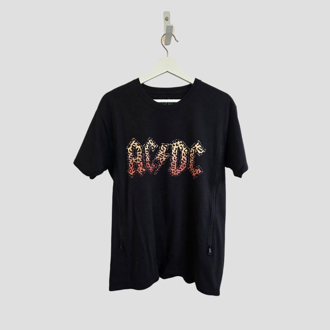 Upcycled black leopard AC/DC band t-shirt (size M) designed for breastfeeding and pumping, featuring a red and orange gradient AC/DC logo on the front, made from eco-friendly materials, hanging on a white hanger against a plain light gray background.