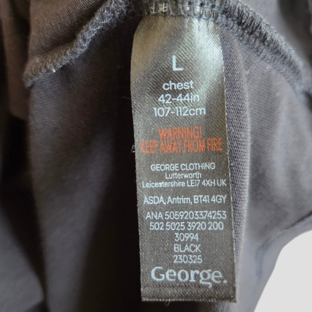 Black clothing tag for the Upcycled Breastfeeding (Nursing) & Pumping Black Iron Maiden Christmas Band t-shirt in size large (chest 42-44in / 107-112cm), featuring a prominent red warning to keep away from fire. The George brand name appears above manufacturing locations and codes listed in white text. This sustainable t-shirt is ideal for those seeking eco-friendly nursing and breastfeeding clothing options.