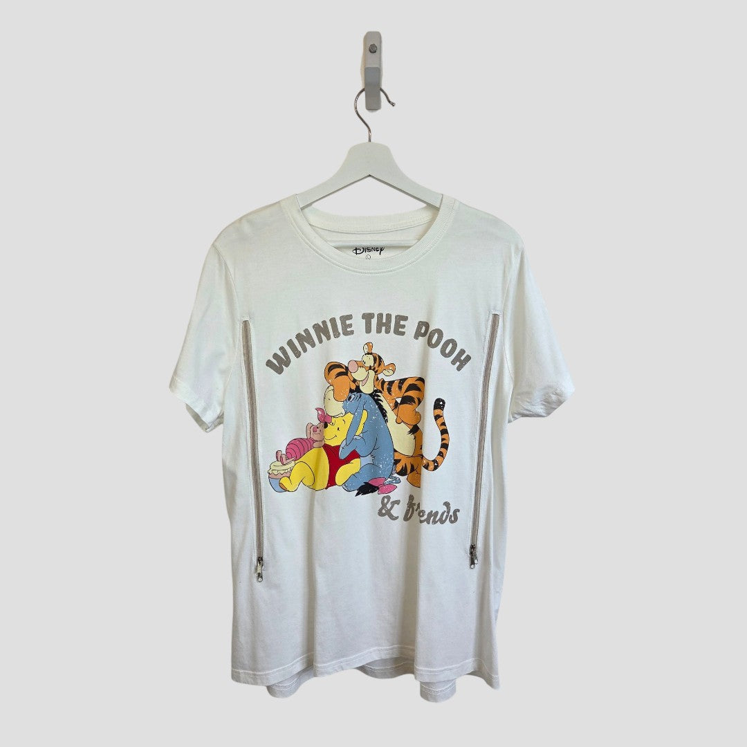Primark Upcycled Breastfeeding (Nursing) & Pumping Cream Winnie the Pooh & Friends t-shirt in size L (UK14/16) features Disney’s beloved characters—Winnie the Pooh, Tigger, Eeyore, and Piglet—illustrated on a hanger. The shirt displays “WINNIE THE POOH & Friends” above and below the design, making it an adorable and affordable choice for fans looking to add functional nursing or breastfeeding clothing to their wardrobe.