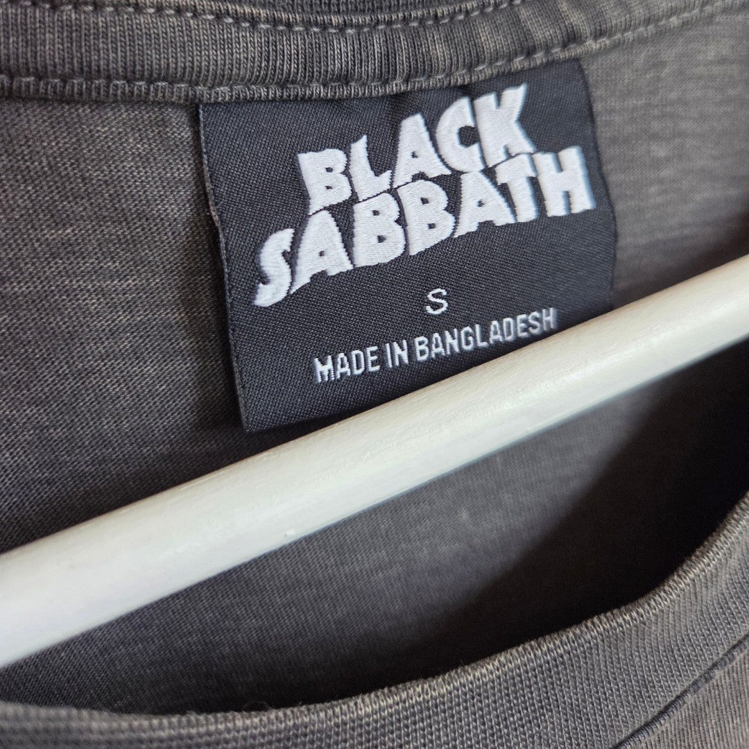 A close-up of a shirt collar with a black label reading Primark and MADE IN BANGLADESH S. A white hanger is visible below the label, showcasing the brand’s commitment to quality in their affordable Upcycled Breastfeeding (Nursing) & Pumping Grey/Orange Lace Black Sabbath Oversized Band t-shirt (size S, product number 100586).