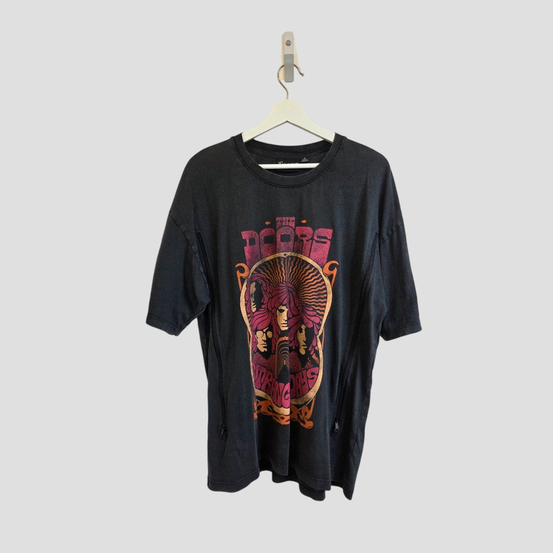 Black oversized band t-shirt—Primark’s Upcycled Breastfeeding & Pumping The Doors Strange Days edition in size S—with a red and orange The Doors graphic on the front, made from eco-friendly materials for the conscious music lover. Displayed on a wooden hanger against a plain light gray background.