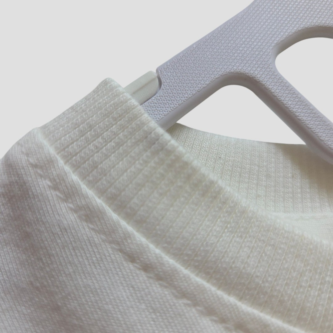 Close-up of a white upcycled Primark “Winnie the Pooh & Friends” breastfeeding and pumping T-shirt (size L, UK14/16), featuring a ribbed crew neck design, displayed on a light gray plastic hanger against a plain background.