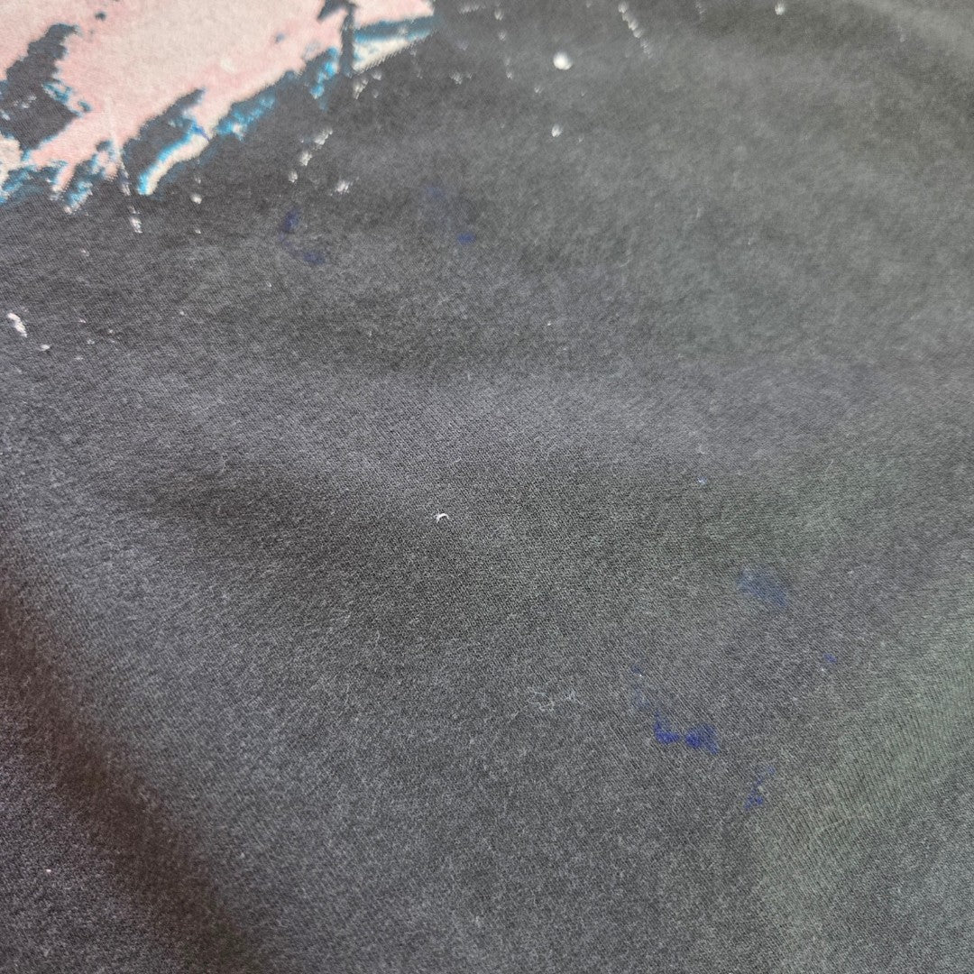 A close-up of the Amplified Upcycled Breastfeeding (Nursing) & Pumping Slipknot Eyeless Band t-shirt (size L, 100590) shows dark fabric with faint blue stains and a partially visible, faded graphic or paint mark in the upper left corner.
