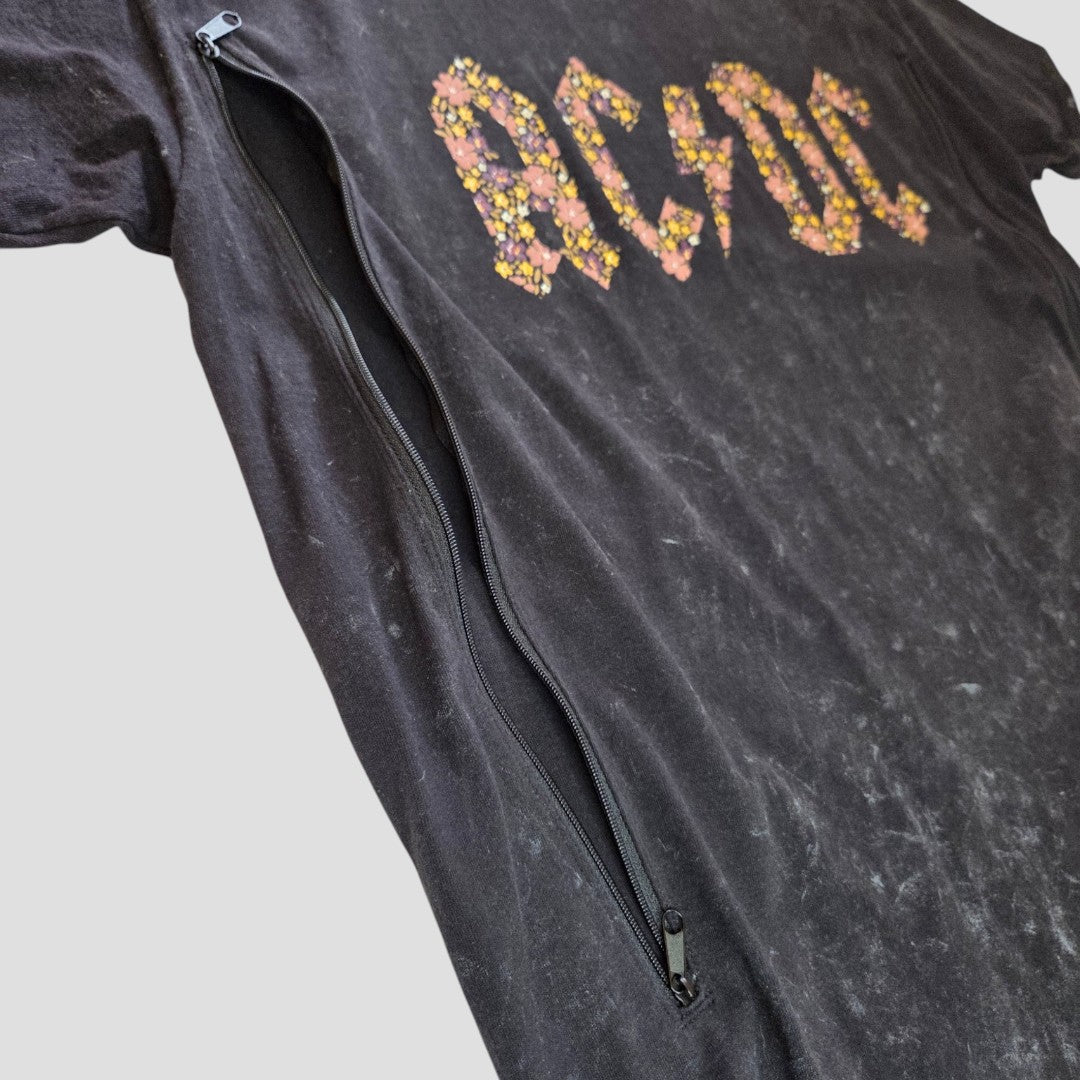 An upcycled black AC/DC band t-shirt in size M featuring a floral logo and a long diagonal front zipper for nursing and pumping. This gently worn, faded shirt offers an affordable, unique style option for breastfeeding parents.