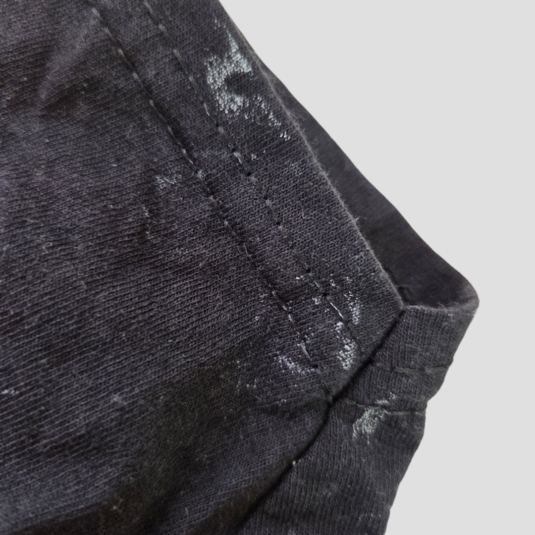 Close-up of an Upcycled Breastfeeding (Nursing) & Pumping Black Floral AC/DC Band t-shirt by AC/DC, size M (100588), showing black fabric with visible white stains and detailed stitching along the seam against a plain light background, emphasizing its eco-friendly and affordable design for nursing mothers.