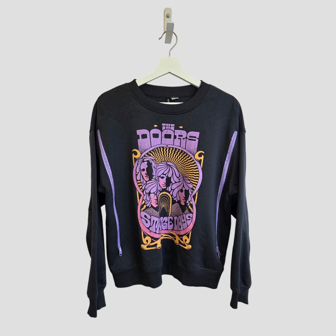 Black H&M upcycled breastfeeding (nursing) and pumping sweatshirt (size M), hanging on a white hanger, featuring a vibrant The Doors graphic with two purple faces and “Strange Days” text in pink and yellow on the front. This stylish band-inspired piece combines rock fashion with convenient features for breastfeeding moms.