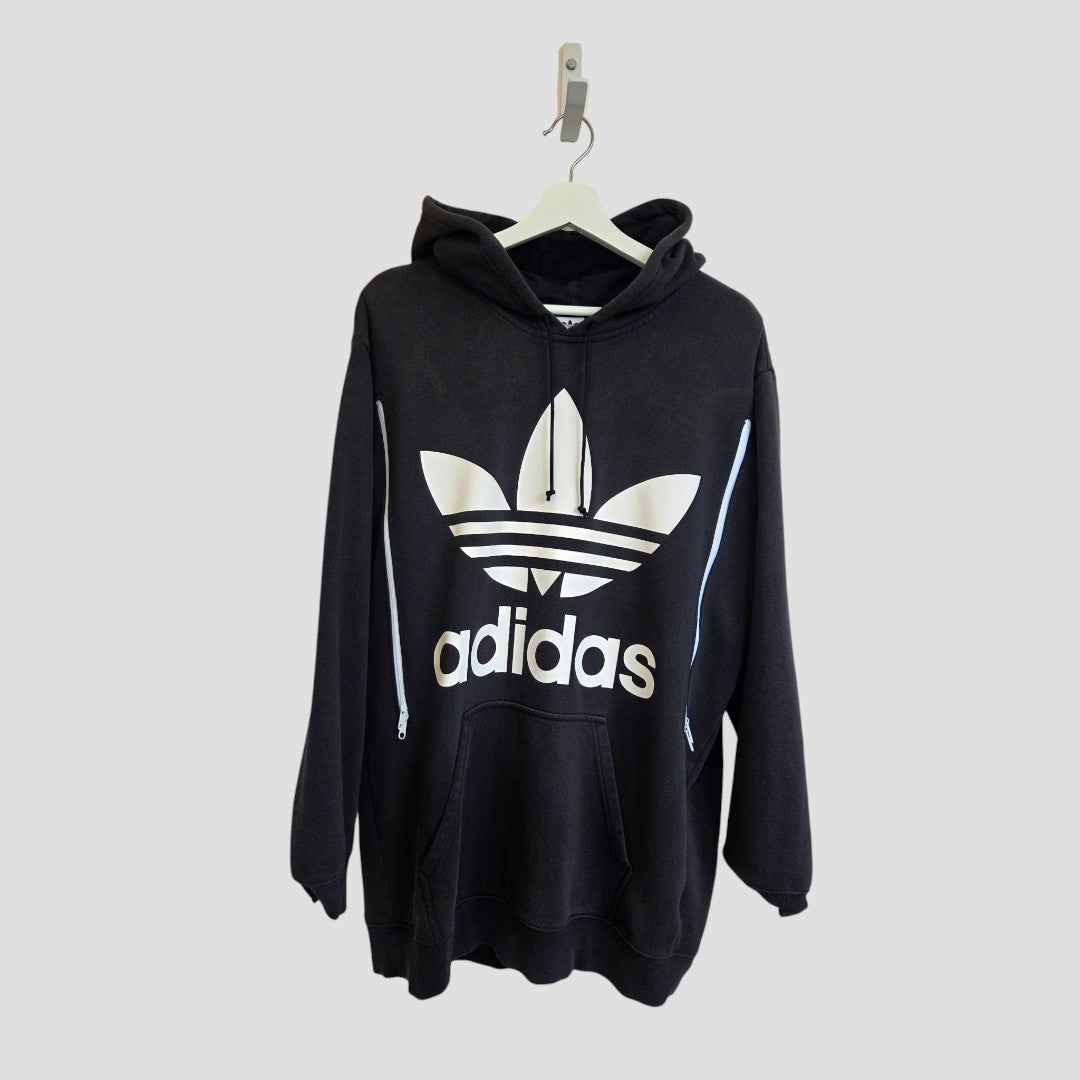 An Upcycled Breastfeeding (Nursing) & Pumping Black Adidas White Logo Hoodie UK16 (100486) by Adidas, featuring a white trefoil logo and “adidas” printed on the front, hanging on a white hanger against a plain light gray background—ideal for those looking for affordable nursing wear that blends comfort, style, and practicality.