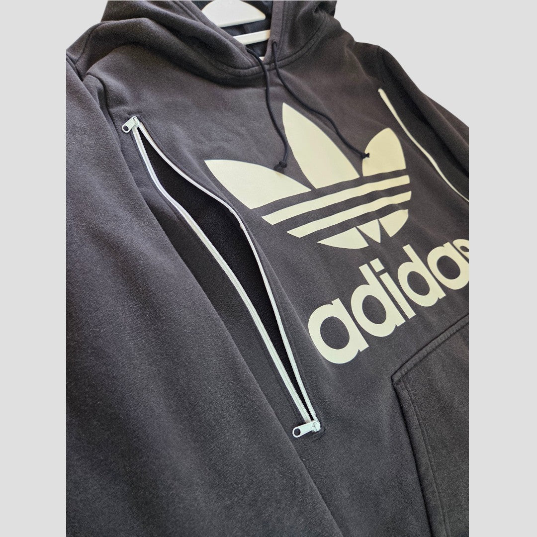 Upcycled Breastfeeding (Nursing) & Pumping Black Adidas White Logo Hoodie UK16 (100486) by Adidas, featuring a white trefoil logo and adidas text, plus a practical white vertical zipper on the upper front left side for easy nursing access. Designed for affordability and functionality, this hoodie is shown hanging against a light background.