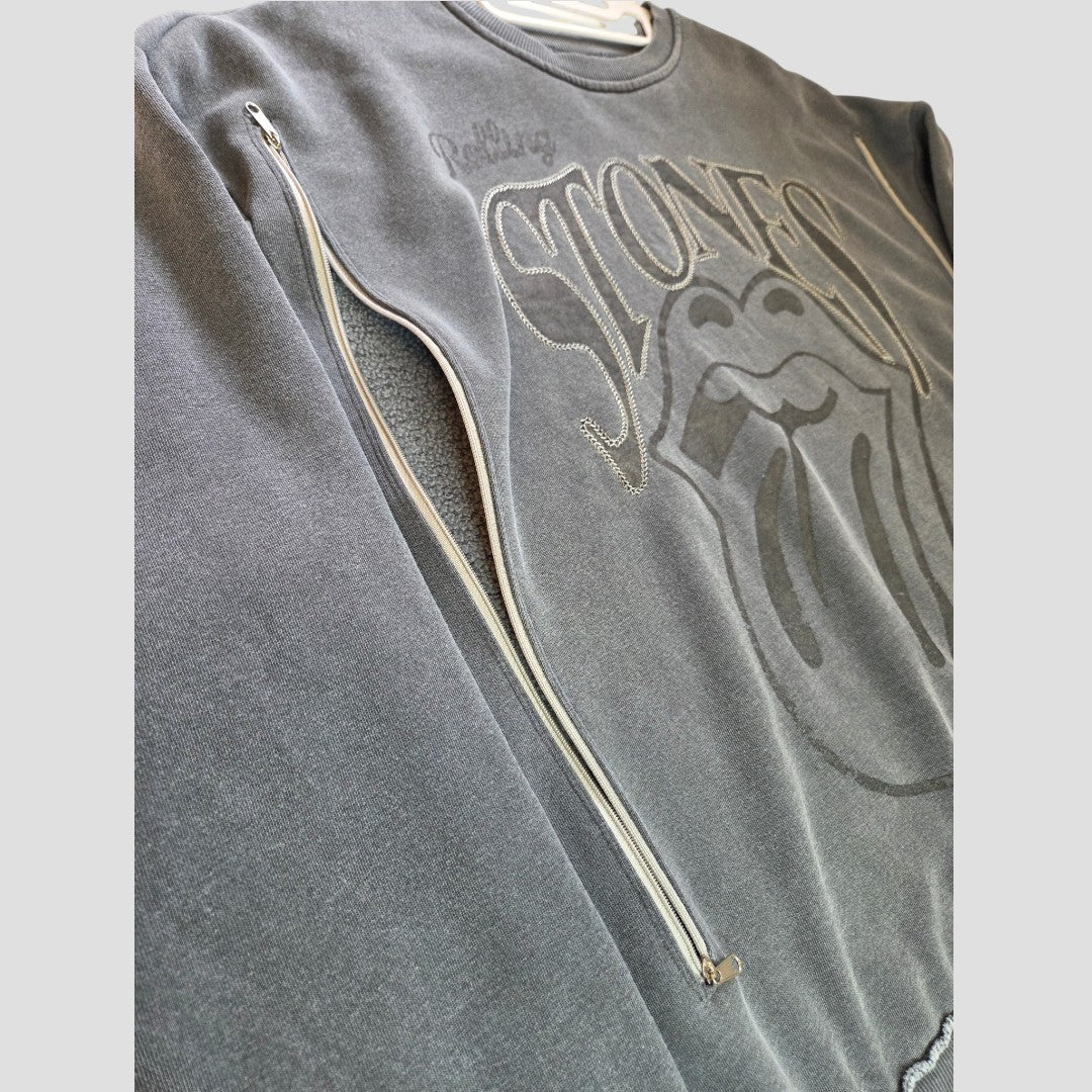 Primark’s Upcycled Breastfeeding (Nursing) & Pumping Grey Embroidered The Rolling Stones Band Sweatshirt (M, 100570) features an embossed tongue logo and iconic branding, along with a discreetly functional silver zipper running diagonally across the chest—making it ideal for breastfeeding or pumping. The affordable shirt is shown laid flat on a light surface.