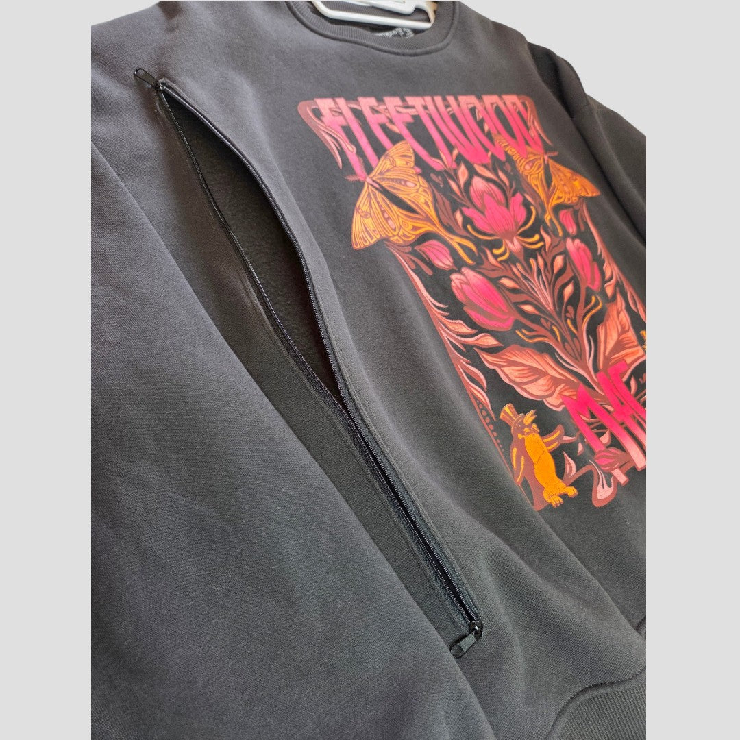 Close-up of an affordable black Primark sweatshirt featuring a visible side zipper and a colorful graphic with flowers, butterflies, and a rabbit in pink, orange, and yellow shades. This upcycled Breastfeeding & Pumping Floral Fleetwood Mac Band Sweatshirt (Size M, UK12/14) offers both style and convenience for nursing mothers.