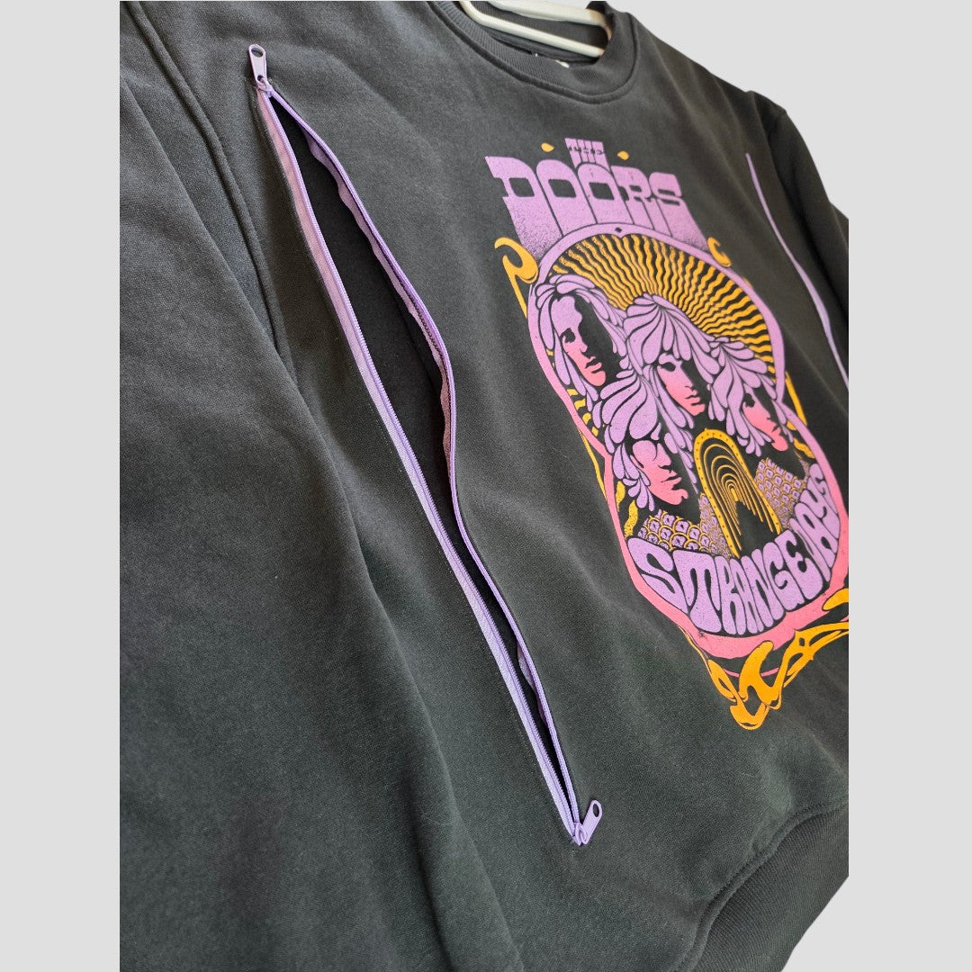 Upcycled black H&M sweatshirt (size M) featuring The Doors “Strange Days” colorful graphic. Stylish purple zippers run diagonally across the chest and sleeve, providing discreet breastfeeding and pumping access. Set against a plain light gray background. Product name: Upcycled Breastfeeding (Nursing) & Pumping The Doors Purple Band Sweatshirt (100452).