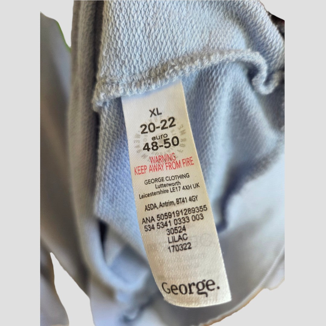A close-up of the label on the Upcycled Breastfeeding (Nursing) & Pumping Blue Floral Paradise Lightweight Sweatshirt in size XL (UK 20/22, Euro 48-50) displays washing instructions and a “keep away from fire” warning. Designed for nursing clothing, the label features the George brand name printed at the bottom.