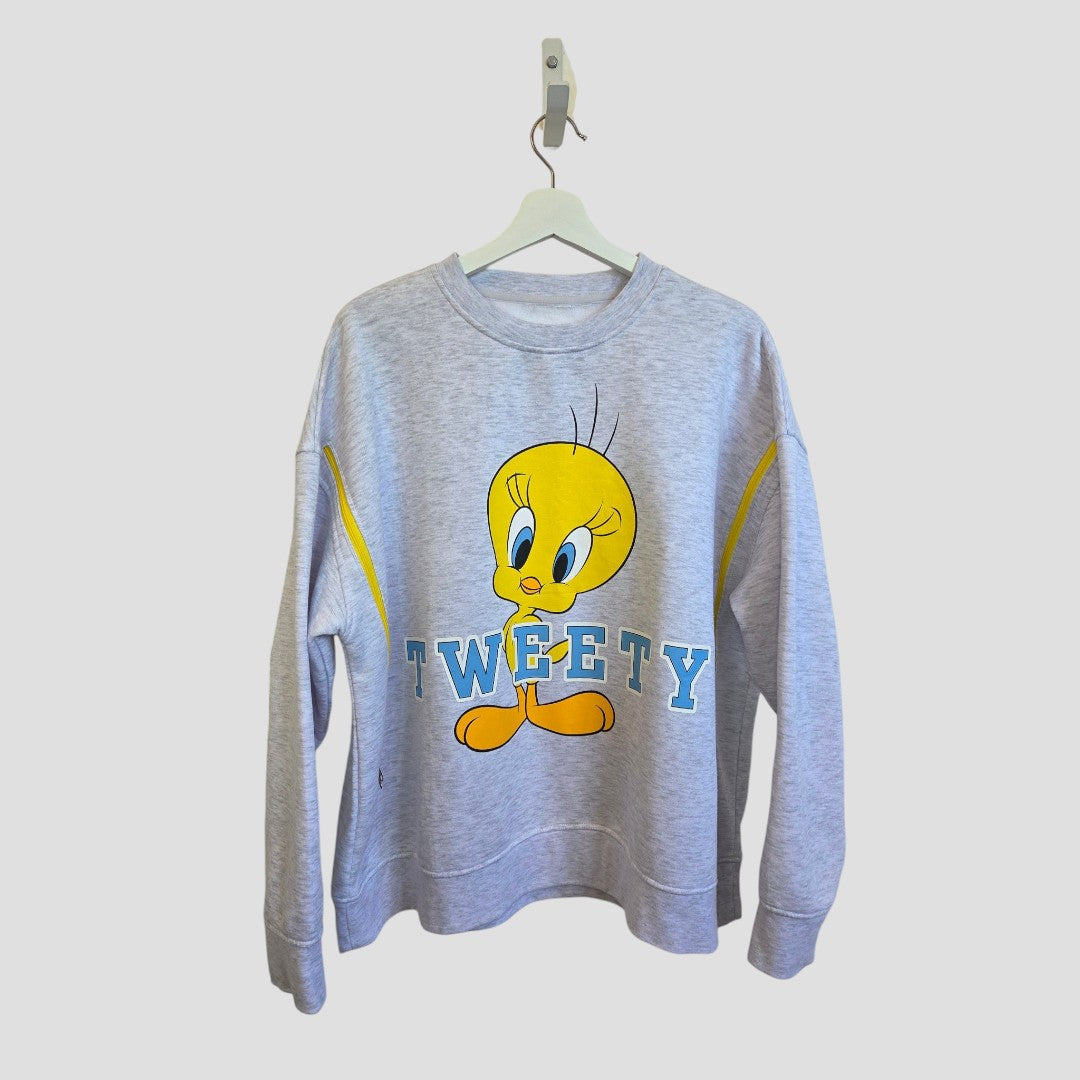 Upcycled Breastfeeding (Nursing) & Pumping Grey Tweety sweatshirt XL (UK18/20) by Primark displayed on a hanger. This affordable piece features a large graphic of Tweety Bird above bold blue “TWEETY” block letters, adding playful style to your everyday wardrobe. The background is plain and light-colored.