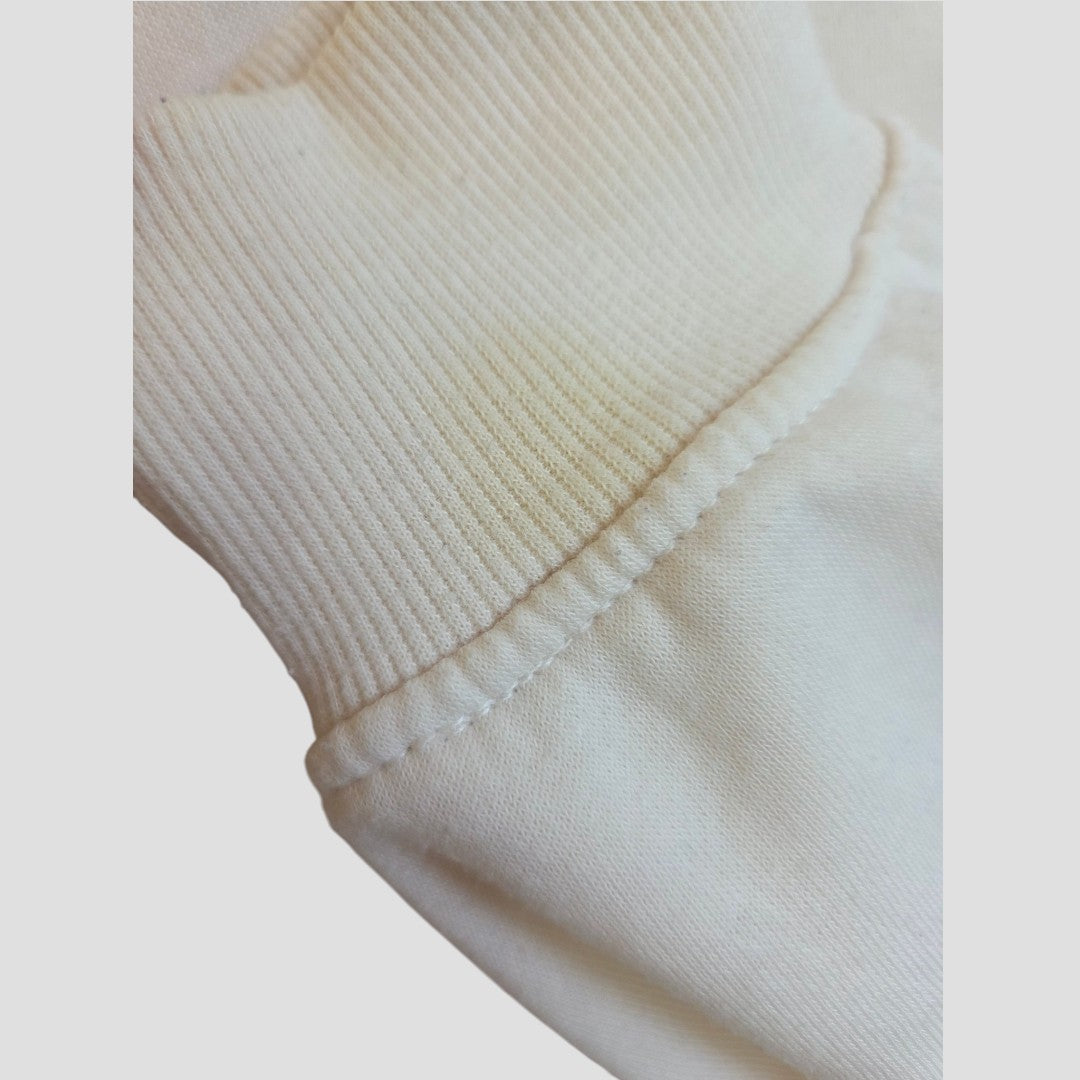 Close-up of a cream-colored fabric with visible stitching and ribbed texture, likely part of a garment such as the Upcycled Breastfeeding (Nursing) & Pumping Cream Wildflowers sweatshirt XL by Primark.