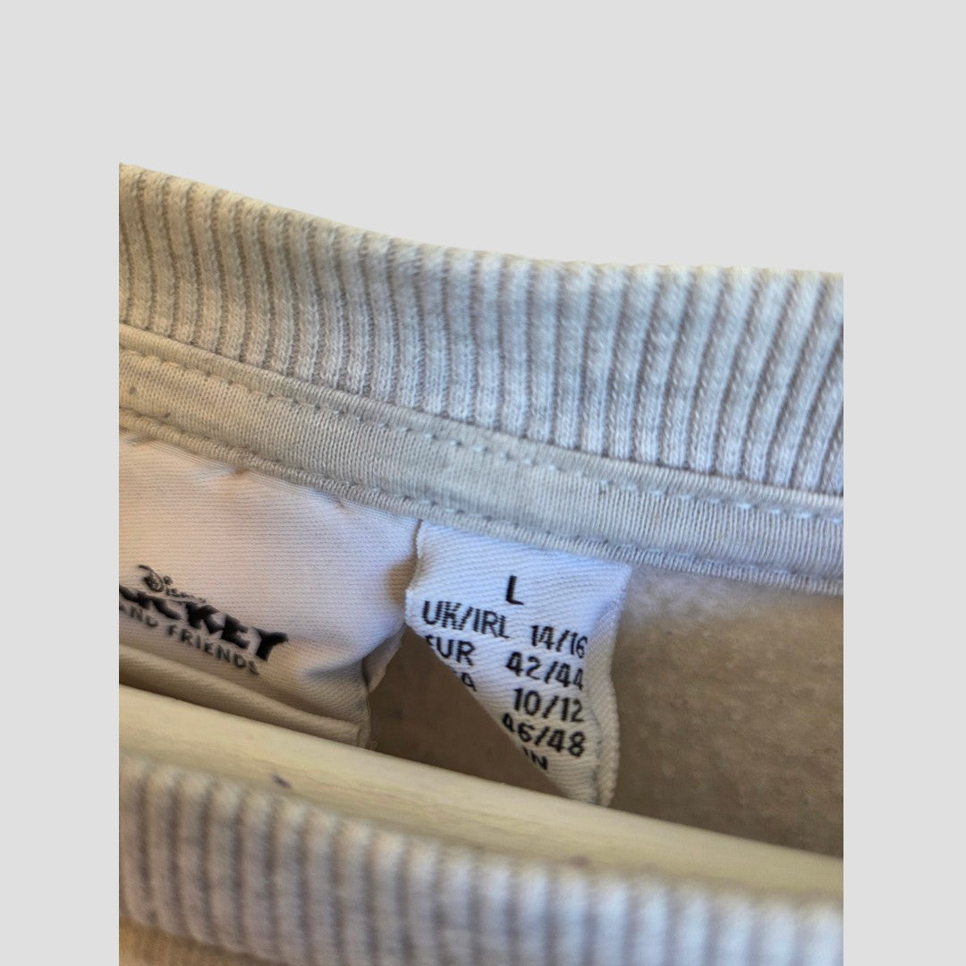 A white clothing tag inside the Upcycled Breastfeeding (Nursing) & Pumping Grey Disney Donald Duck sweatshirt by Primark displays size information: UK/IRL 14/16, EUR 42/44, US 10/12, MEX 16/18. Ribbed white fabric is visible around the collar area—making this affordable nursing wear an ideal choice for those seeking comfort and functionality.
