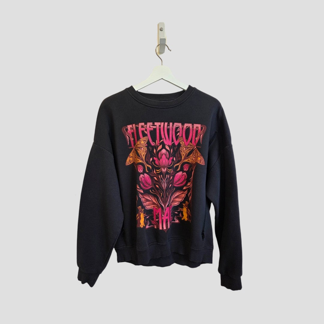 A black upcycled breastfeeding and pumping sweatshirt by Primark hangs on a white hanger, showcasing a vibrant pink and orange floral Fleetwood Mac graphic on the front. Designed in size M (UK12/14), this eco-affordable nursing sweatshirt combines comfort and style for breastfeeding clothing needs. The background is plain light gray.