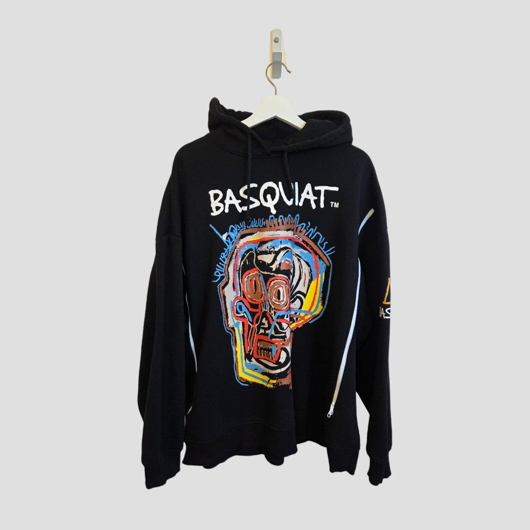 Primark Upcycled Breastfeeding (Nursing) & Pumping Black Basquiat Graphic Hoodie XL (UK18/20) displayed on a hanger against a plain gray background. Featuring a colorful abstract skull artwork with the text “BASQUIAT” on the chest, this stylish hoodie is crafted from eco-friendly materials and includes a small patch on the left sleeve.