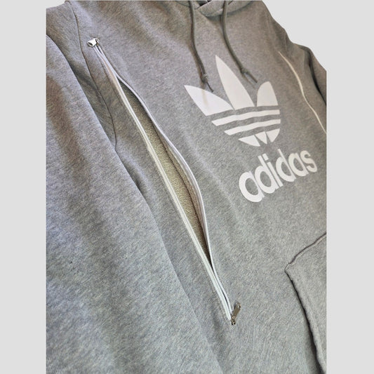 Introducing the Upcycled Breastfeeding (Nursing) & Pumping Grey/White Adidas Hoodie XL (100494), a stylish gray Adidas hoodie featuring a distinctive white zipper running diagonally across the chest near the iconic printed Adidas logo. Thoughtfully designed for convenience, this affordable hoodie functions as discreet nursing apparel, with a front pocket and adjustable hood drawstrings for added comfort and style.