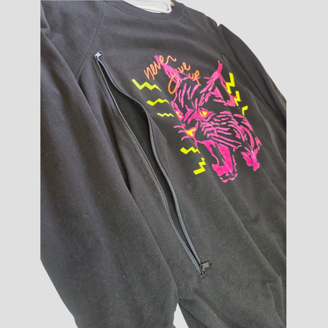 The Nine+ Quarter Upcycled Breastfeeding (Nursing) & Pumping Black Tiger Maternity Sweatshirt (size M, 100648) features a bold pink and yellow roaring big cat graphic with lightning bolts and a vertical side zipper on the chest for easy nursing or pumping access—perfect as an organic cotton, stylish maternity and breastfeeding top.