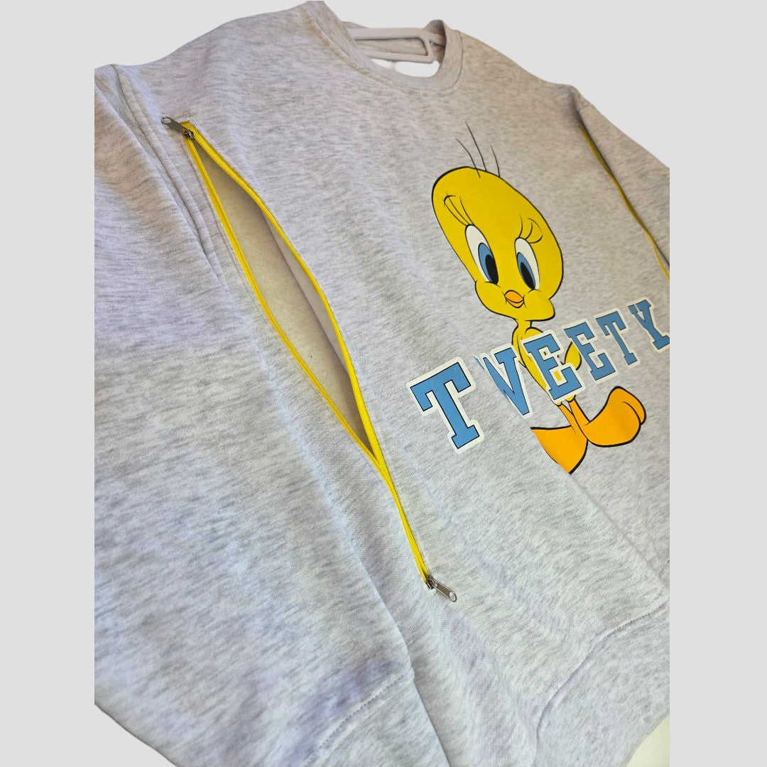 The Upcycled Breastfeeding (Nursing) & Pumping Grey Tweety sweatshirt XL (UK18/20) by Primark features a large Tweety character graphic and TWEETY text, with yellow zippers running vertically on both sides for easy nursing access—offering a stylish and affordable option for breastfeeding clothing.