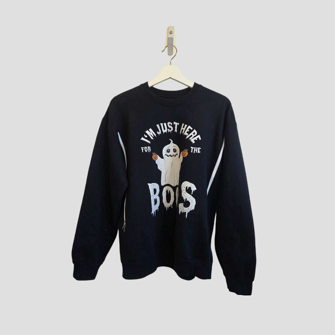An upcycled black “Here for the Boos” breastfeeding and pumping sweatshirt (size M, 100652) is shown on a hanger, featuring a cute ghost graphic and playful white lettering—an affordable and fun example of functional nursing wear.
