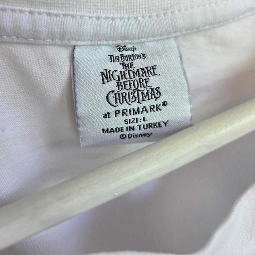 Close-up of a white clothing label stitched inside an upcycled breastfeeding & pumping The Nightmare Before Christmas festive t-shirt by Primark, size L, made in Turkey—an eco-affordable choice for fans seeking sustainability in their wardrobe.