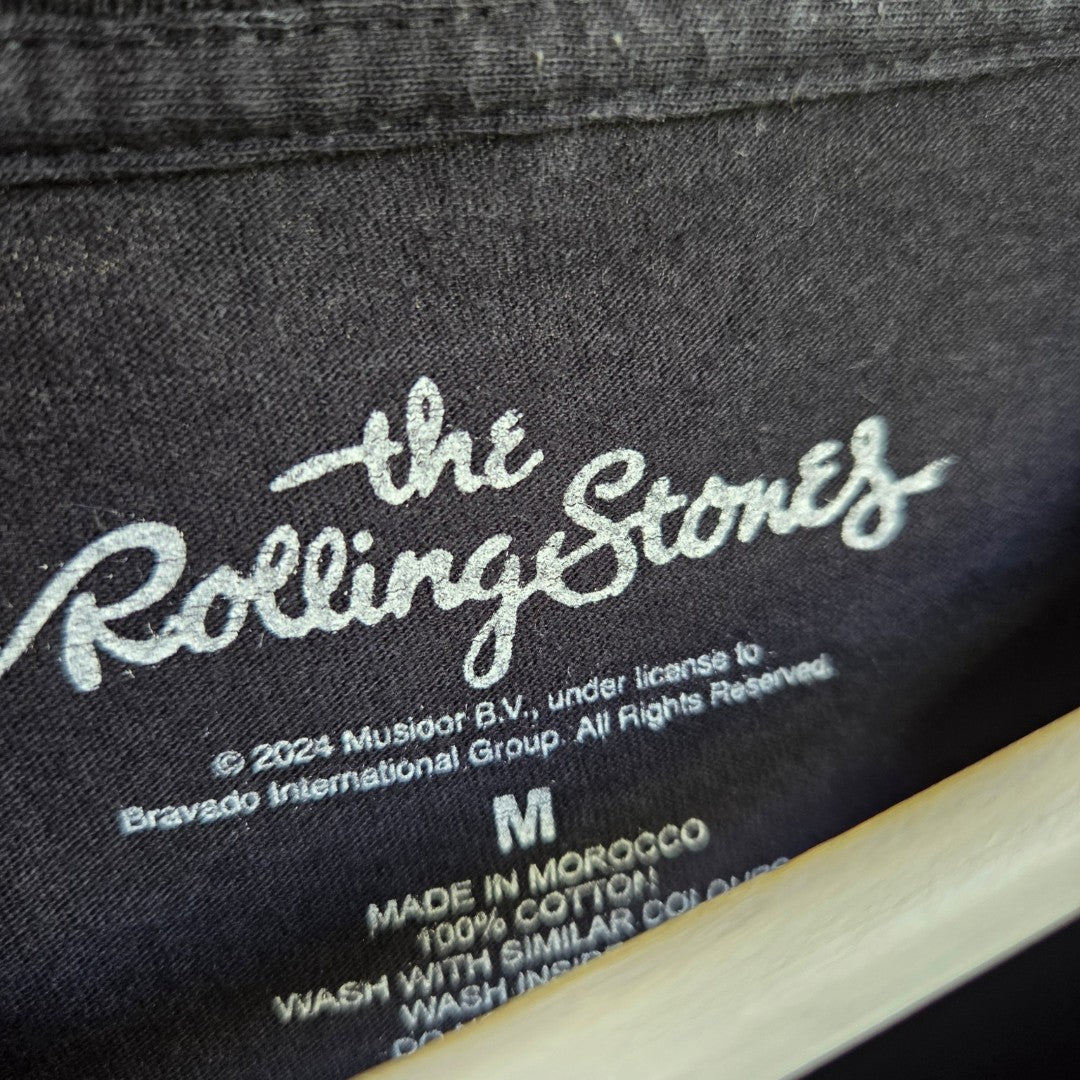 Black neck label of an Upcycled Breastfeeding (Nursing) & Pumping Black Colourful The Rolling Stones Tongue t-shirt M (100621), showing size M and The Rolling Stones logo.
