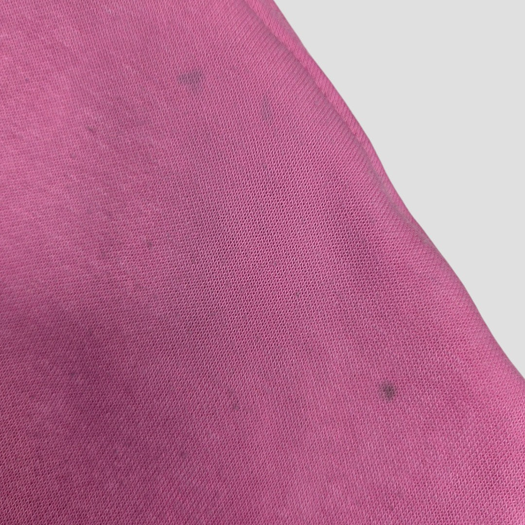 Close-up of pink eco nursing clothing fabric from the Upcycled Breastfeeding (Nursing) & Pumping Pink Def Leppard Band sweatshirt S (100651), featuring faint dark spots.